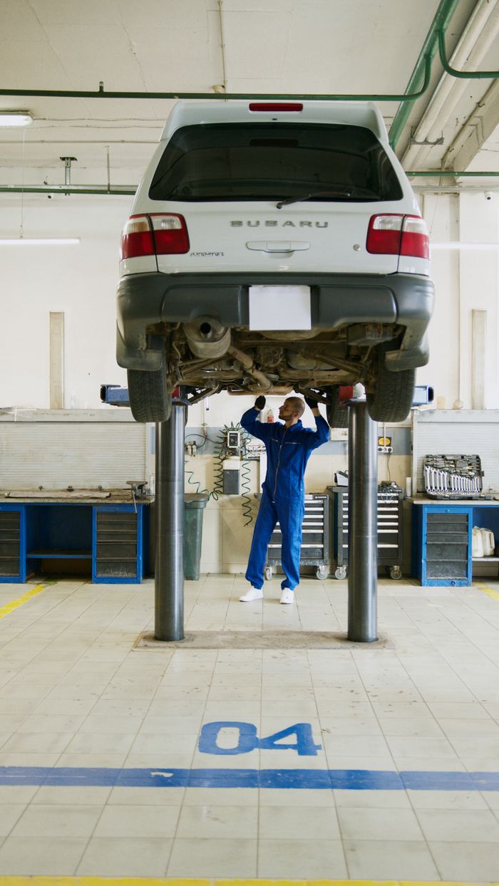 A professional mechanic checks a car on a lift in an auto repair shop.