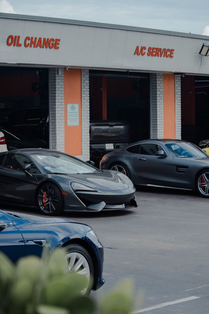 Luxury cars parked outside an automotive service center with visible service signs.